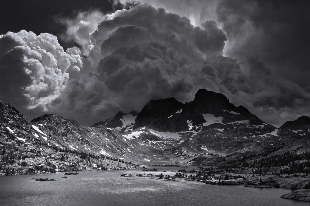 Photo en noir et blanc de Ansel Adams  représentant un paysage montagnard avec d'énormes nuages (initiationphoto.com)