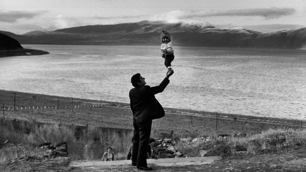 Photo en noir et blanc d'Henri Cartier-Bresson représentant un homme tenant sur sa main un jeune enfant debout (initiationphoto.com)