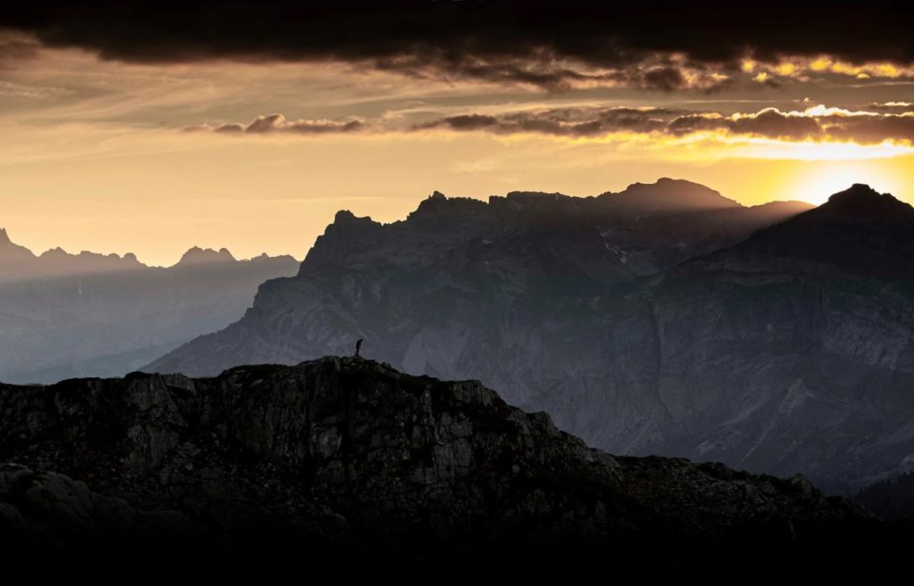 Photo couleur de Matt Hardy représentant un paysage de montagne au coucher du soleil, un homme marchant sur la crête de l'une d'entre elles (initiationphoto.com)