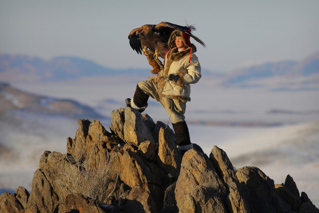 Photo couleur de Timothy Allen représentant un jeune foconnier debout sur des rochers tenant son oiseau (initiationphoto.com)