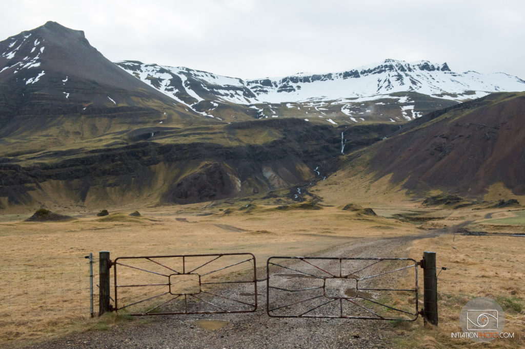 Photo d'un paysage en couleur représentant une barrière fermée donnant sur des montagnes en Islande (initiationphoto)