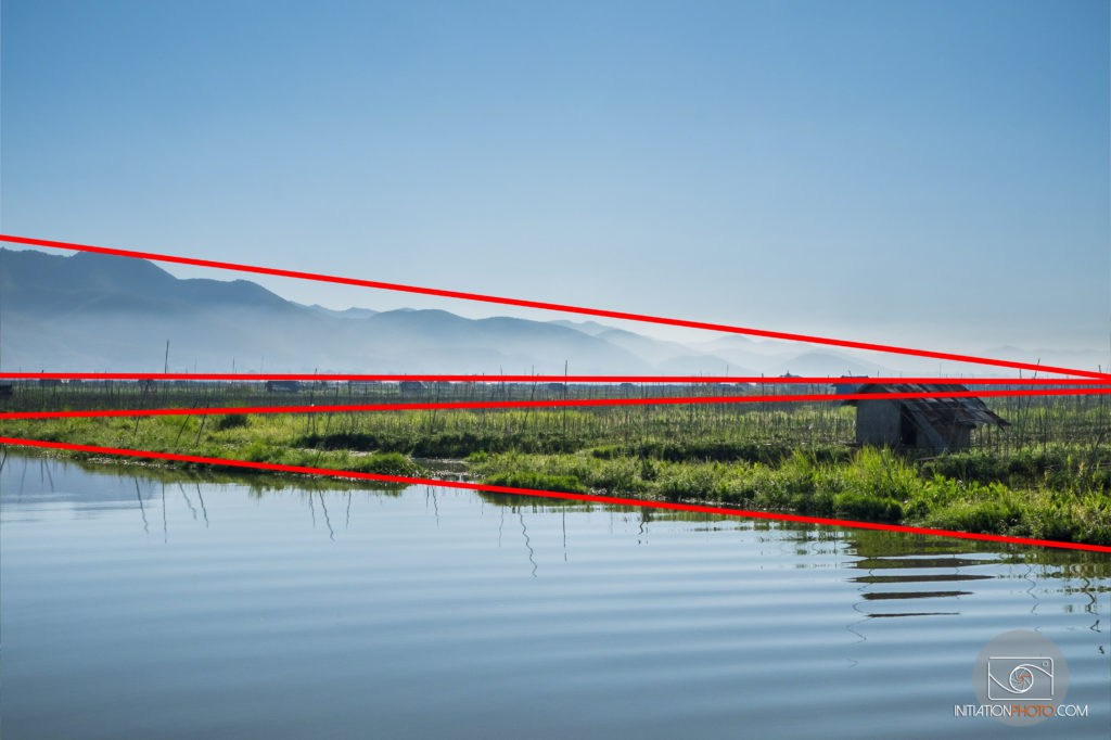 Photo couleur d'un paysage au Myanmar au bord du Lac Inlé avec les montagnes à l'arrière-plan, la même que la précédente mais avec des lignes rouges pour montrer les lignes de la composition (initiationphoto)