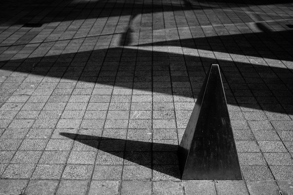 Photo en noir et blanc d'un plot triangulaire et son ombre portée, image très graphique