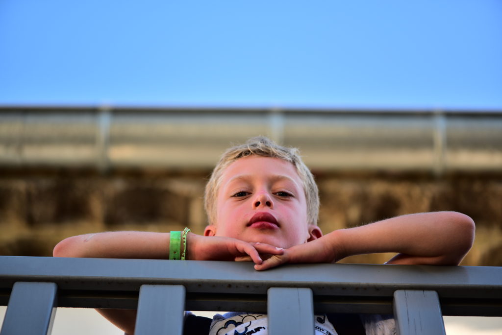 Photo couleur non traitée d'un garçon qui regarde par dessus du garde-corps d'une terrasse en hauteur