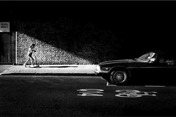 Une photo en noir et blanc d'Alan Schaller représentant une demi voiture et d'une personne placées idéalement par rapport à la lumière