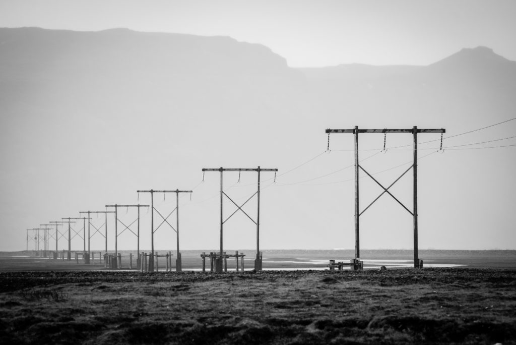 Photo en noir et blanc d'une vue en perspective de lignes à haute tension en Islande