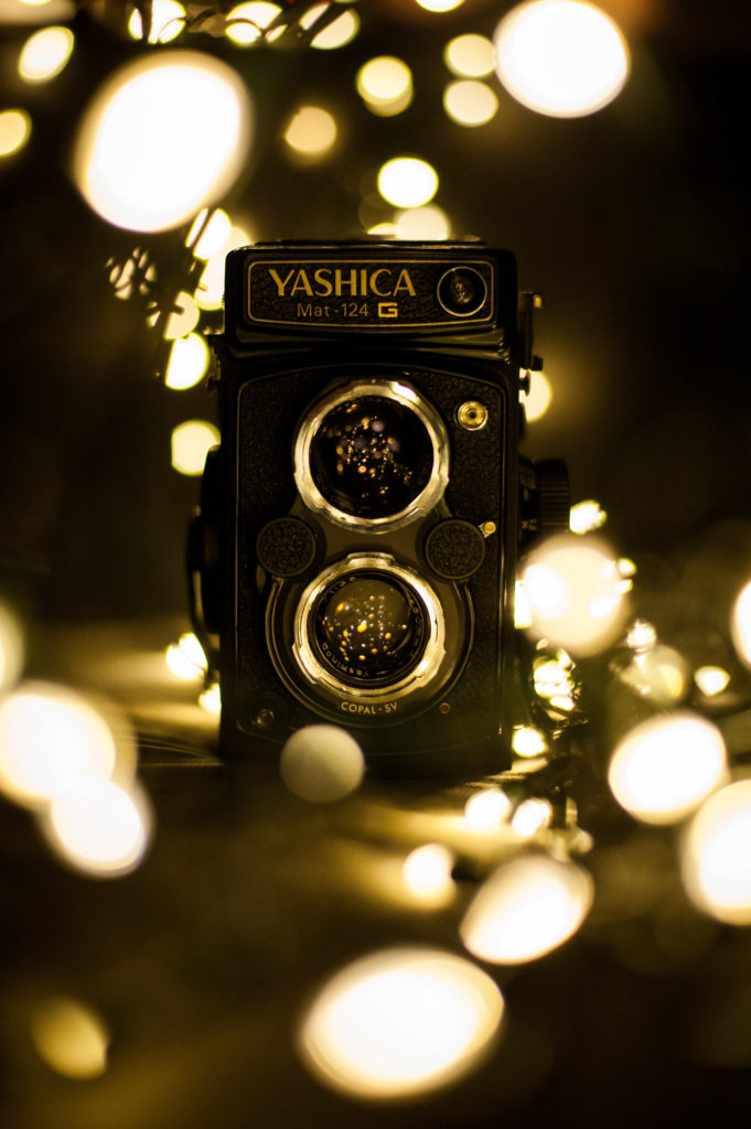 Photo monochrome d'un ancien appareil photo à double objectif, modèle Yashica Mat124G avec des bulles de lumière tout autour