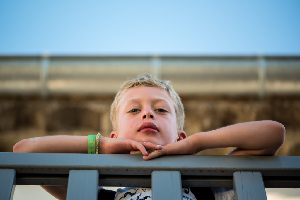 Portrait serré d'un jeune garçon accoudé à un balcon pris à 105mm de longueur focale