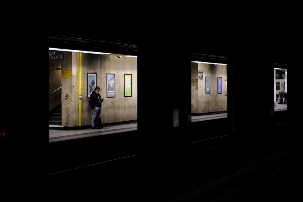 Photo couleur prise dans une gare souterraine et représentant trois carrés illuminé avec une personne en train d'attendre